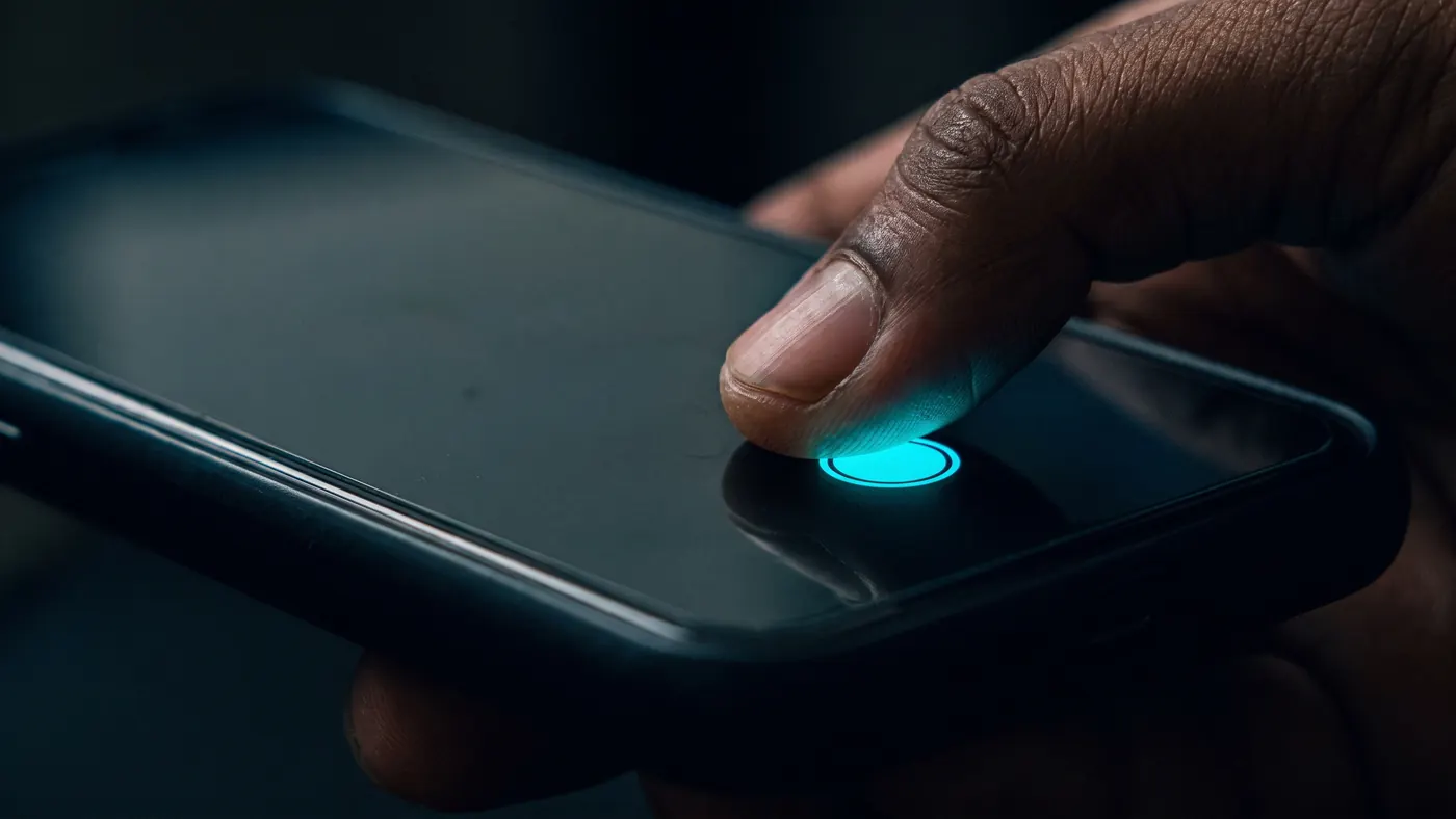 Un dedo apretando el botón cian de marcar en la pantalla del celular.